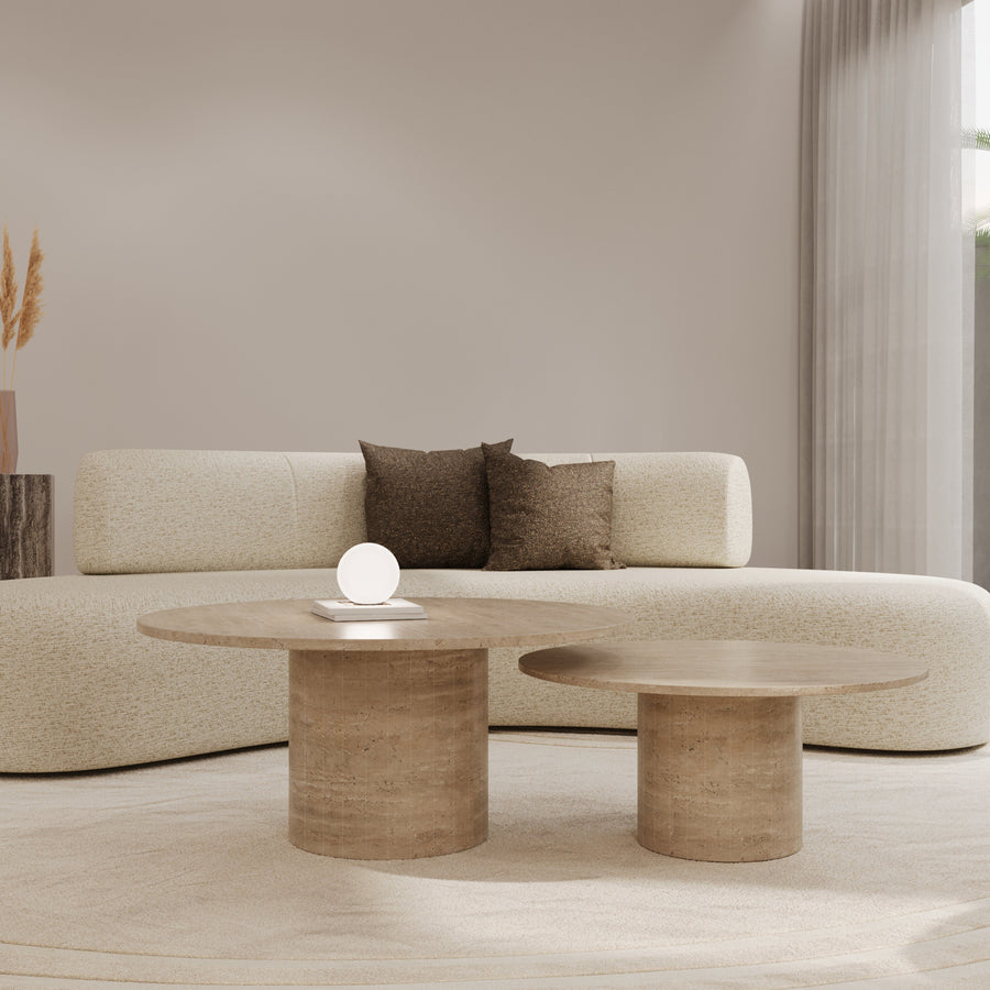 Travertine nesting coffee tables in front of a curved sofa by The Gallery Home