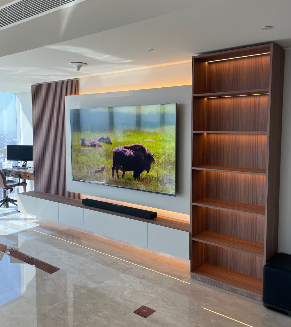 Bespoke media wall and lit walnut shelving installed by The Gallery Home